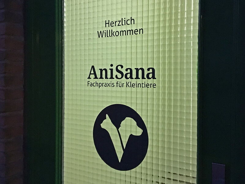 Beleuchtete Tür "AniSana" im Dunkeln